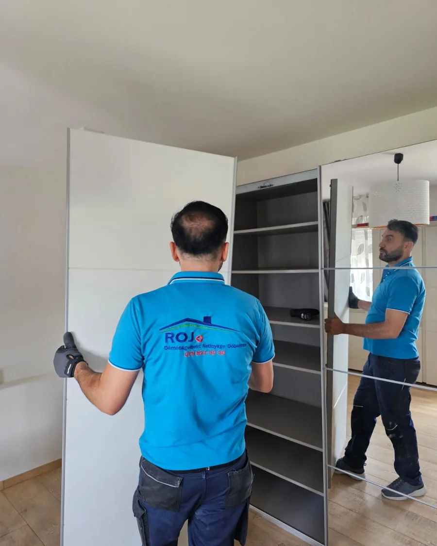 Deux déménageurs de ROJ portent un panneau d'armoire dans l'appartement